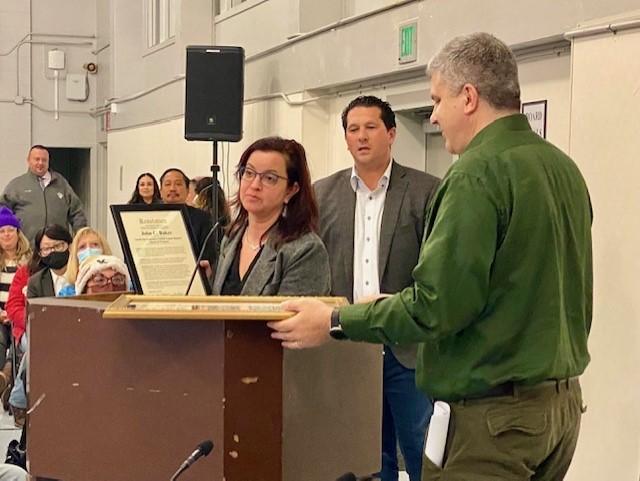 San Mateo County Board of Supervisors President David Canepa looks on as SSFUSD School Board President John Baker is presented with a commendation after serving out his term.